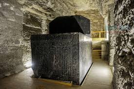 A large stone sarcophagus inside the underground gallery of the Serapeum of Saqqara, Egypt, illuminated by modern lighting